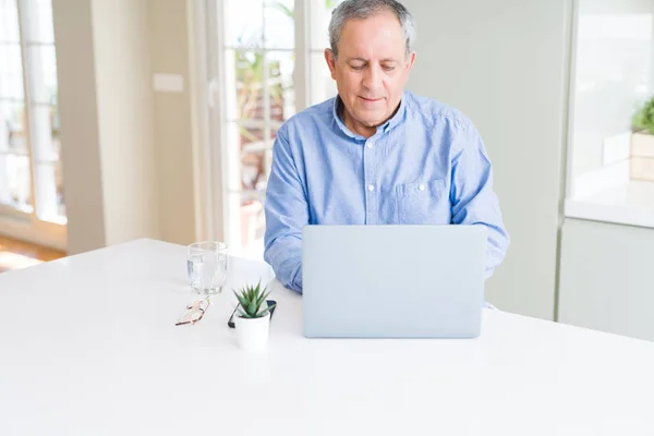 Hombre mayor guapo usando el ordenador portátil y sonriendo — Foto de Stock