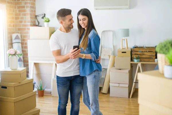 Junges Paar zieht mit Smartphone lächelnd in ein neues Haus — Stockfoto
