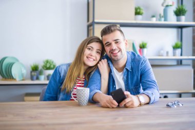 Genç çift rahatlatıcı bir fincan kahve içme ve smartph kullanarak