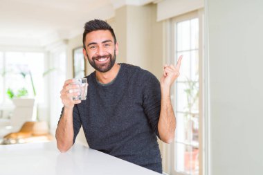 Yakışıklı İspanyol adam yan el ve parmak ile işaret çok mutlu bir bardak su içme