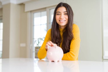 Kadın gibi Piggy banka içinde bir sikke koyarak gülümseyen yakın