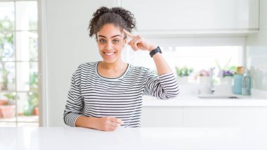 Afro saçlı güzel afro-amerikan kadın rahat çizgili kazak giyen gülümseyerek tek parmak, harika bir fikir ya da düşünce, iyi bellek ile baş işaret