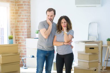 Orta yaş yaşlı çift yorgun görünümlü ve çapraz kolları ile depresyon sorunları ile sıkılmış düşünme etrafında kutuları ile yeni bir eve hareket.