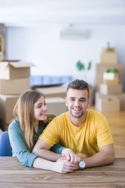 Junges schönes Paar sitzt zu Hause auf dem Tisch und umarmt sich — Stockfoto