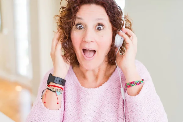 Ανώτερη Γυναίκα Φορώντας Ακουστικά Ακούγοντας Μουσική Τρομαγμένα Μια Έκπληξη Πρόσωπο — Φωτογραφία Αρχείου
