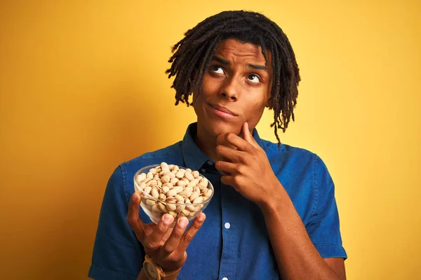 Joven Afroamericano Con Rastas Comiendo Pistachos Sobre Fondo Amarillo Aislado — Foto de Stock