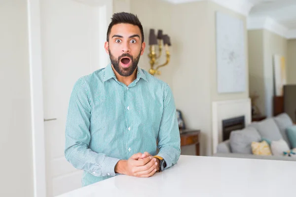 Handsome hispanic man at home afraid and shocked with surprise expression, fear and excited face.