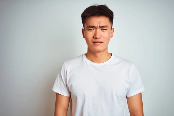 年轻的亚洲中国男子穿着T恤站在孤立的白色背景怀疑和紧张 皱眉不安 因为问题 消极的人 — 图库照片
