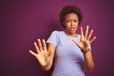 Izole mor arka plan üzerinde afro saçlı genç güzel Afro-Amerikan kadın korkmuş ve korku ifade ile korkmuş elleriyle jest durdurmak, şok içinde bağırarak. Panik kavramı.