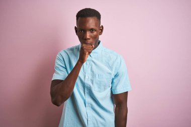 Izole pembe arka plan üzerinde duran mavi rahat gömlek giyen Afro-Amerikan adam rahatsız duygu ve soğuk veya bronşit için bir belirti olarak öksürük. Sağlık kavramı.