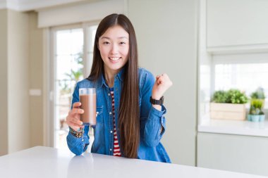 Güzel Asyalı kadın çikolata milkshake taze bir bardak içme gurur çığlık ve zafer ve başarı kutluyor çok heyecanlı, duygu tezahürat