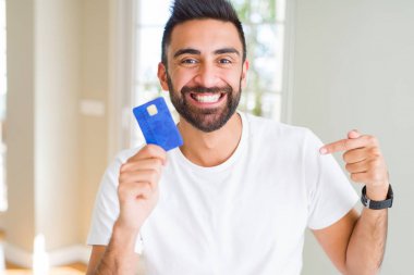 Yakışıklı İspanyol adam sürpriz yüz kendini işaret parmak ile kredi kartı tutan