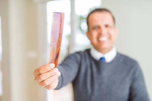 Középkorú férfi gazdaság és bemutató hajfésű, miközben mosolyogva a — Stock Fotó