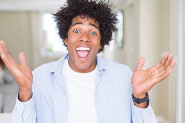 Afrika kökenli Amerikalı adam evde çılgın ve başarı için hayran kaldırdı Kollarını açarak kutluyor ve heyecanlı çığlık gözleri açık. Kazanan kavramı