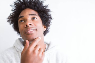 Afro-Amerikan adam beyaz izole arka plan üzerinde çene üzerinde soru, dalgın ifade düşünme el ile. Düşünceli bir yüzle gülümsüyor. Şüphe kavramı.