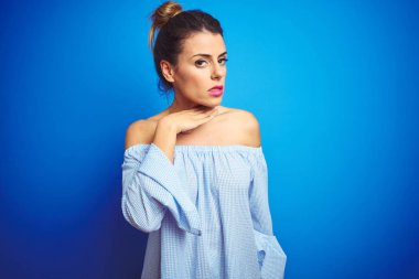 Mavi izole arka plan bıçak gibi el ile boğaz kesme üzerinde topuz saç modeli giyen genç güzel kadın, öfkeli şiddet ile saldırganlık tehdit