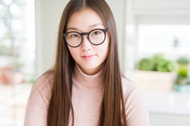 Gevşek ciddi ifade ile yüzünde gözlüklü güzel Asyalı kadın. Basit ve çapraz silah ile doğal