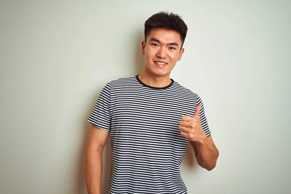 孤立した白い背景の上に立つストライプのTシャツを着た若いアジア人の男性は 手で幸せな親指を上げるジェスチャーをしています 成功を示すカメラを見て式を承認する — ストック写真