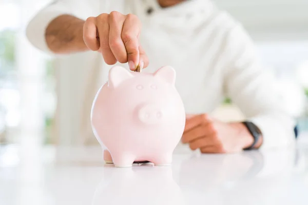 Homem colocando uma moeda dentro de poupança bancária porquinho para investimento — Fotografia de Stock