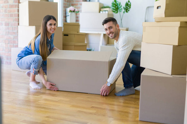 Красивая молодая пара переезжает в новый дом, держа в руках большой кардбоа
