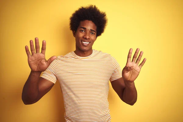 美国男子与非洲裔头发穿着条纹T恤站在孤立的黄色背景显示和指向手指9号 同时微笑自信和快乐 — 图库照片