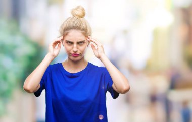 Yüksek sesle müzik gürültü rahatsız ifade parmaklarıyla kulaklarıyla kapsayan izole arka plan üzerinde mavi t-shirt giyen genç güzel sarışın ve mavi gözlü kadın. Sağır kavramı.