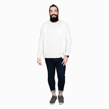 Uzun saçlı ve sakallı genç adam yüzünde mutlu ve serin bir gülümseme ile sportif sweatshirt giyiyor. Şanslı kişi.