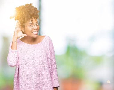 Gözlüklü bir işitme söylenti ya da dedikodu için dinleme kulak üzerinde el ile gülümseyen izole arka plan üzerinde güzel genç Afro-Amerikan kadın. Sağırlık kavramı.
