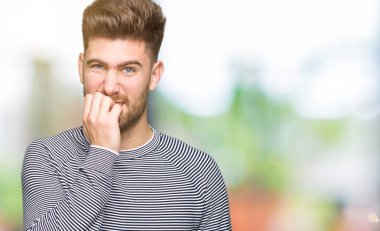 Genç yakışıklı adam stresli ve gergin ile çizgili süveter giyen tırnak ısırma dudaklarından eller. Anksiyete sorunu.