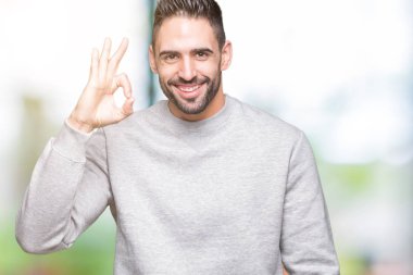 Genç yakışıklı adam izole arka plan el ve parmaklar ok işaretiyle yapıyor olumlu gülümseyen üzerinde kazak giyiyor. Başarılı ifade.