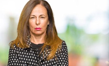 Yüz çapraz kolları olan moda ceket şüpheci ve sinir, onaylamayan ifade giyen güzel orta yaş kadın. Negatif kişi.