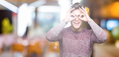 Dilini, parmaklarının arasından baktığını yapışmasını dürbün gibi ok jest yapıyor izole arka plan üzerinde gözlük takan yakışıklı delikanlı. Deli ifade.