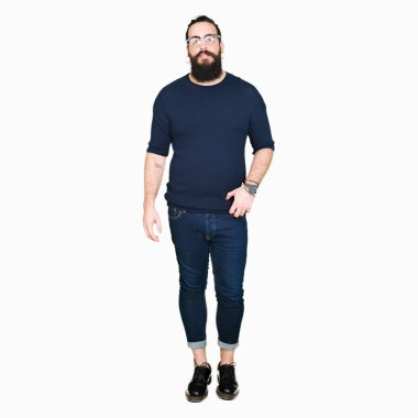 Uzun saç ve sakal gevşek ciddi ifade ile yüzünde gözlüklü genç hipster adam. Basit ve doğal kameraya bakıyor.