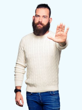 Elin avuç durağı şarkı yapıyor kış kazak giyen genç hipster adam. Negatif ve ciddi bir jest yüz ifadesiyle uyarı.