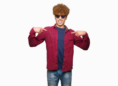 Yüzünde gülümseme ile kendinden emin görünüyorsun, kendini gururlu ve mutlu parmakları ile işaret güneş gözlüğü takıyor afro saçlı Genç yakışıklı adam.