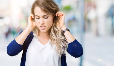 Güzel sarışın genç kadın parmakları ile yüksek sesle müzik gürültü rahatsız ifade kulaklarıyla kapsayan izole arka plan üzerinde. Sağır kavramı.