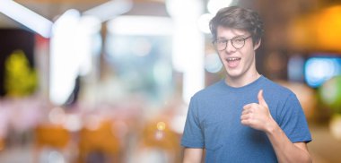 Hareketi el ile mutlu yaşasın yapıyor izole arka plan üzerinde gözlük takan yakışıklı delikanlı. Kameraya bakarak başarı gösteren ile ifade onaylama.