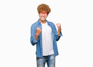 Gülümseyen ve başarı için çığlık yakışıklı delikanlı afro saçlı gözlüklü çok mutlu ve heyecanlı kaldırdı, silah ile kazanan jest yapıyor. Kutlama kavramı.