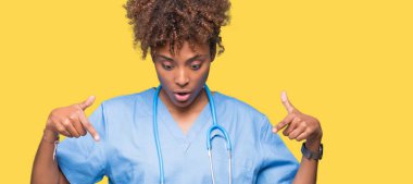 Genç Afro-Amerikan doktor kadın izole arka plan işaretleme aşağı reklam, sürpriz yüz ve açık ağız gösterilen parmakları ile