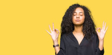 Kıvırcık saçlı zarif elbise genç güzel kız rahatla ve gülümseyen gözlerle kapalı parmak jestle meditasyon yapıyor. Yoga kavramı.