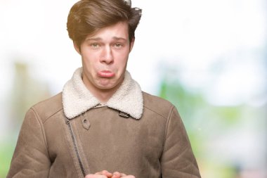 Genç yakışıklı adam izole arka plan üzerinde kış ceket giyen depresif ve sıkıntı için endişe, kızgın ve korkmuş ağlıyor. Hüzünlü ifade.