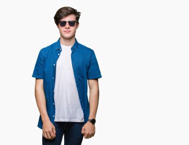 Genç yakışıklı adam yüzünde ciddi bir ifade ile izole arka plan üzerinde güneş gözlüğü takıyor. Basit ve doğal kameraya bakıyor.