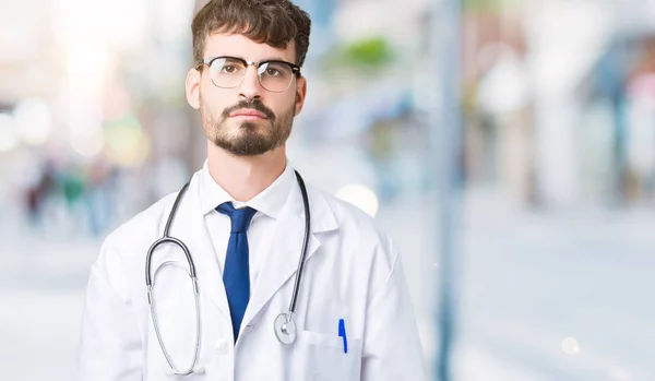 年轻的医生在孤立的背景上穿上医院外套 脸上严肃的表情放松 简单而自然地看着相机 — 图库照片