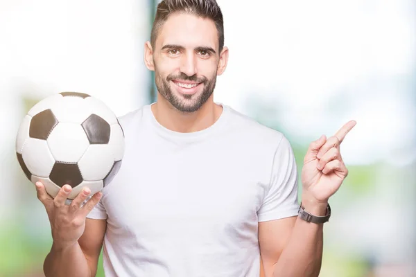 若い男側の手と指で指す非常に幸せの孤立した背景にサッカー サッカー ボールを保持しています — ストック写真