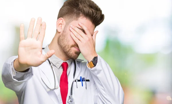 Young Handsome Doctor Man Wearing Medical Coat Covering Eyes Hands — Stock Photo, Image