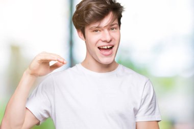 Büyük ve büyük boy işaret, ölçü birimi sembol gösteren ellerle eller izole arka plan üzerinde rahat beyaz t-shirt giyen genç yakışıklı adam. Kameraya bakarak gülümsüyordu. Ölçüm kavramı.