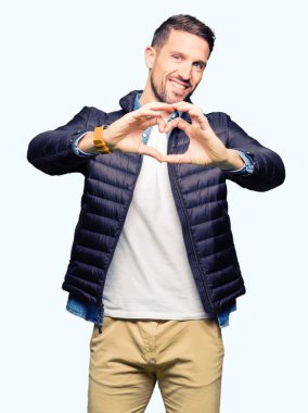 Yakışıklı adam aşık kalp simgesi ve elleriyle şekil gösteren gülümseyen kış palto giyiyor. Romantik kavramı.