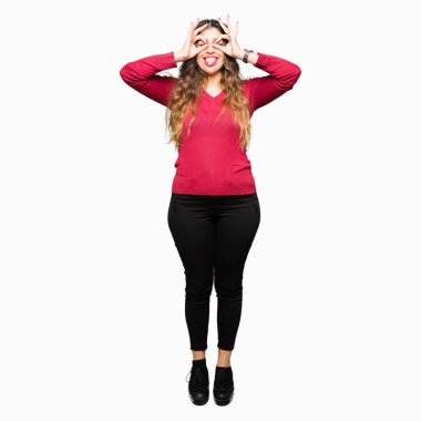 Kırmızı kazaklı, dilini parmaklarının arasından baktığını yapışmasını dürbün gibi ok jest yapıyor giyen genç güzel kadın. Deli ifade.