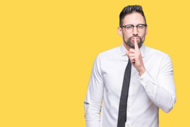 Dudaklarında parmak ile sessiz olmanı izole arka plan üzerinde gözlük takan genç yakışıklı iş adamı. Sessizlik ve gizli kavramı.