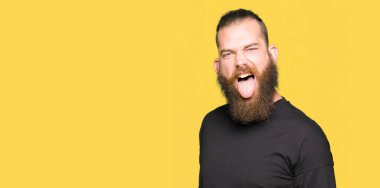 Rahat t-shirt yapışma dil giyen genç sarışın adam out komik ifade ile mutlu. Duygu kavramı.